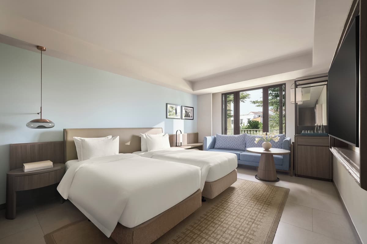 Una habitación de hotel moderna con una cama grande, un sofá, un televisor y vistas al exterior.