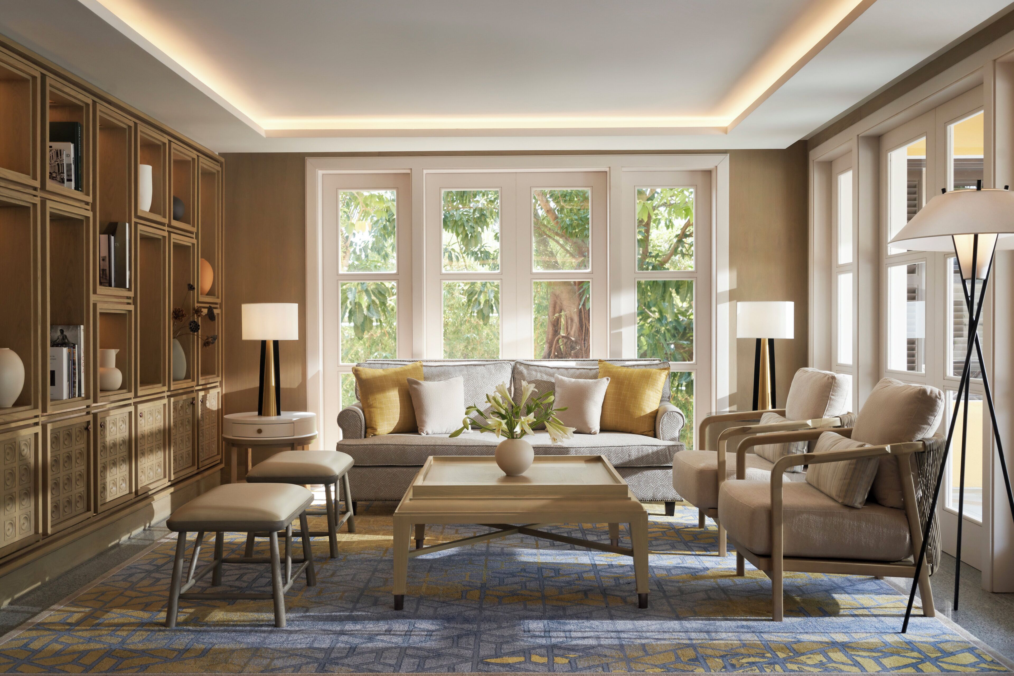 Un salón luminoso con sofá, sillones, una mesa de centro y una estantería.