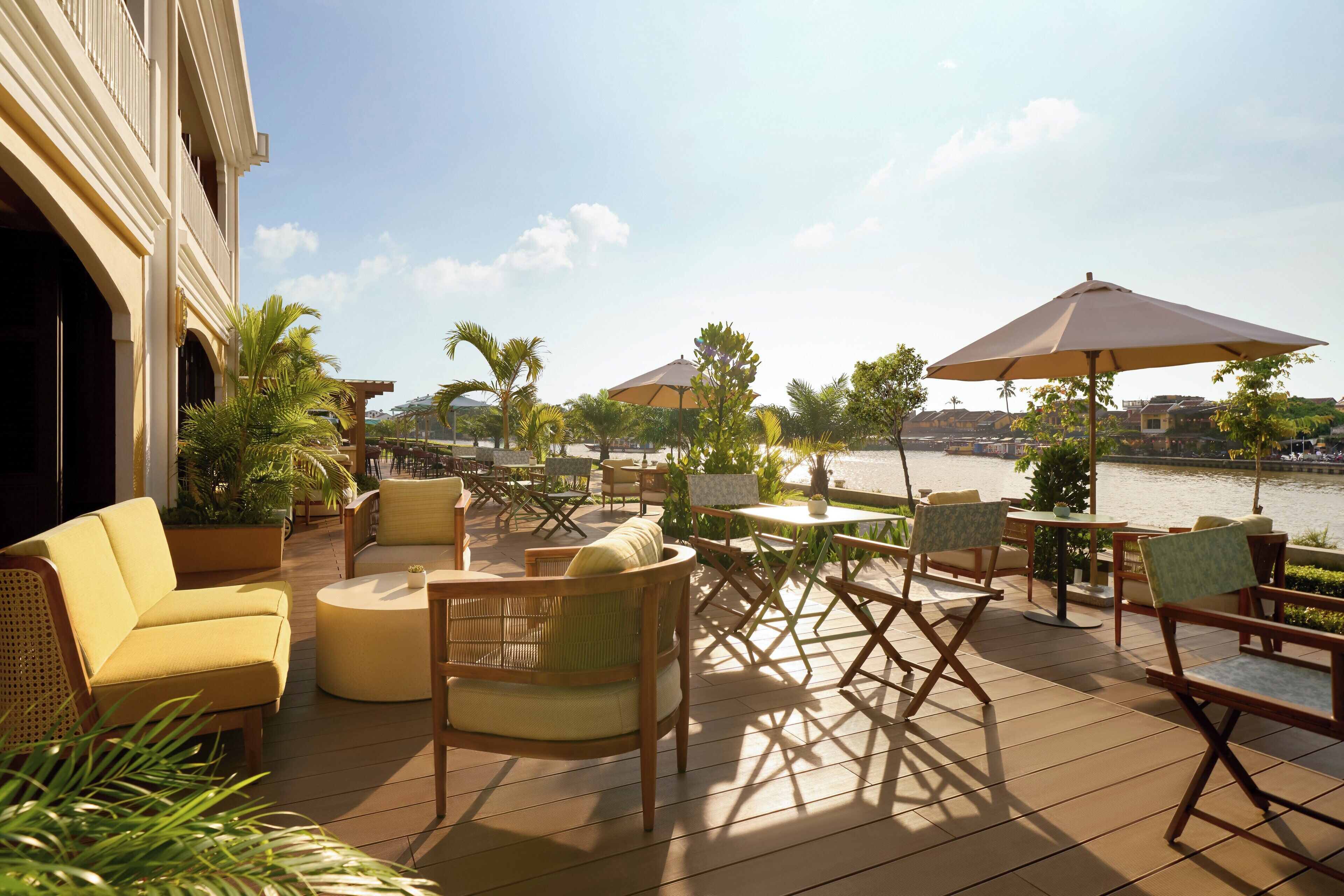 Une terrasse avec des sièges extérieurs, comprenant des chaises et des tables, donnant sur un plan d’eau.