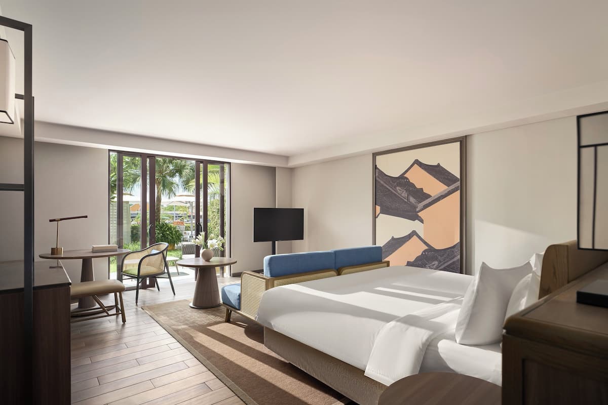 Habitación de hotel con una cama grande, un escritorio con silla, una mesita y un televisor.
