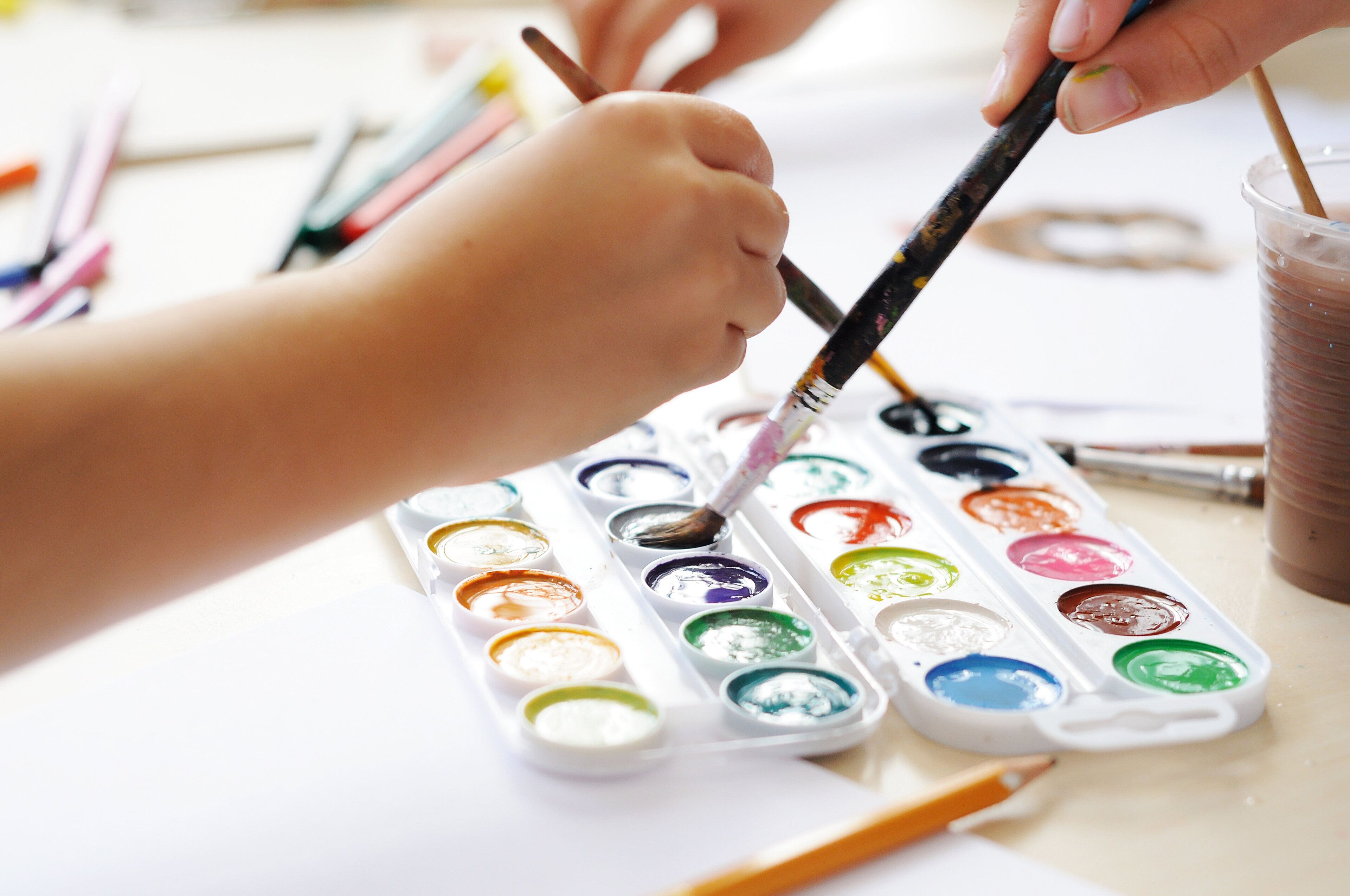 Primer plano de manos pintando con acuarelas.