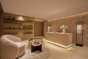 A modern reception area with a stone wall, a reception desk, a plush armchair, and a small round table with decorative items.