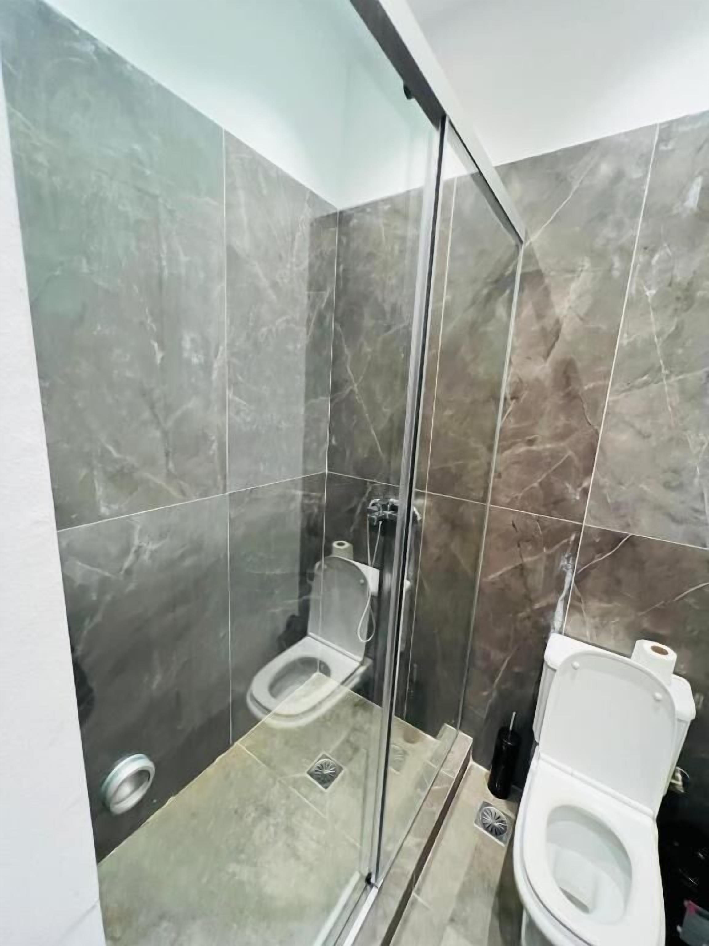 Un baño moderno con cabina de ducha de vidrio, inodoro y bidé.