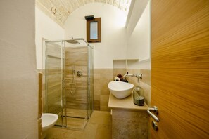 A bathroom with a glass shower enclosure, a sink, and a toilet.