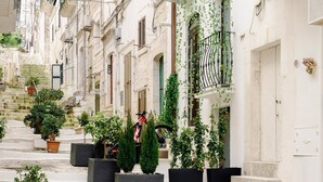 A narrow street with buildings, potted plants, and a bicycle. - La Maison Ostuni (chromotherapy and balcony) (Ostuni)