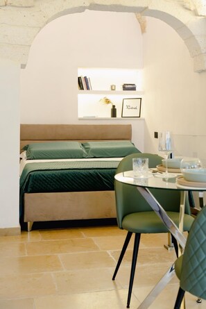 A cozy room with a bed, a small table with a glass, and a chair.