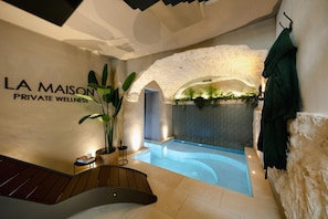 A spa area with a pool, a staircase, and a wall with the text 'LA MAISON PRIVATE WELLNESS'.