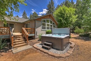 A wooden cabin with a hot tub, a staircase, and a deck.