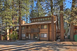 A two-story wooden building with a balcony, surrounded by tall pine trees. - Summit Run by Destination Big Bear: Walking Distance to Snow Summit! Close to the Lake! Minutes from the Village! (Big Bear Lake)