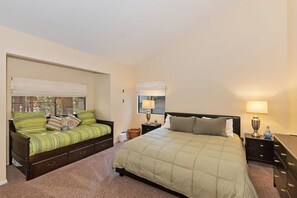 Une chambre à coucher avec un lit, un canapé, une table de chevet et une lampe.