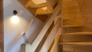 Una escalera de madera con una lámpara en la pared.