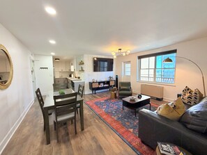 A modern living room with a sofa, coffee table, and a dining area with chairs and a table. - Downtown High-Rise, 19th floor with City Views (Atlanta)