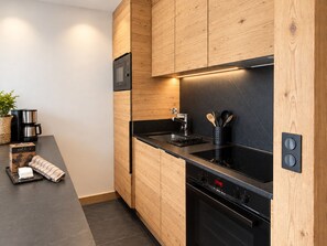 Una cocina moderna con gabinetes de madera, encimera negra y electrodomésticos de acero inoxidable.