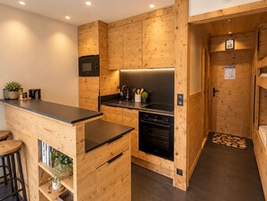 Cozinha moderna com armários de madeira, bancada preta e eletrodomésticos embutidos.