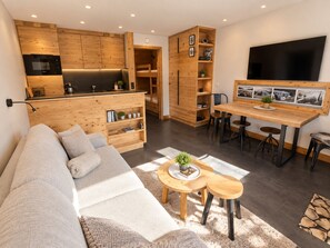 Um espaço de estar moderno com sofá, mesa de centro e área de jantar.