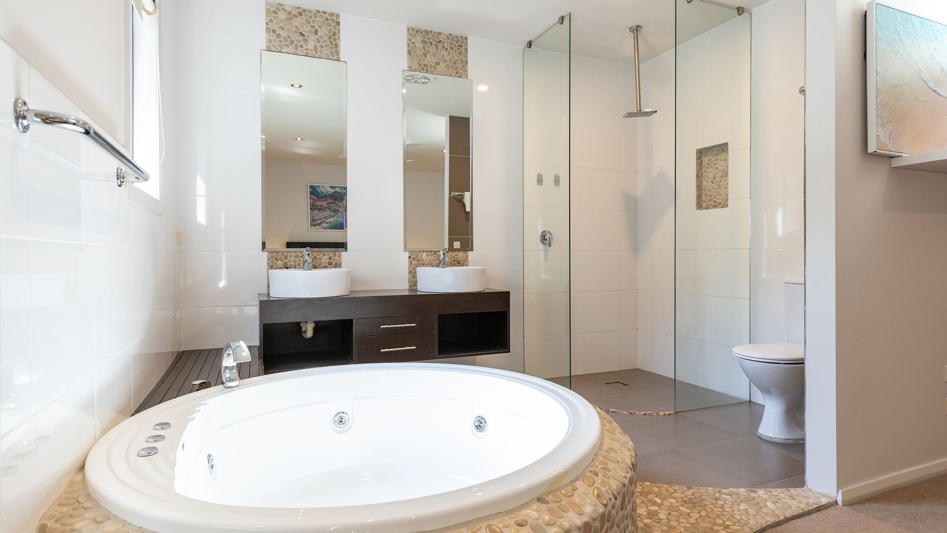 Een moderne badkamer met een vrijstaand bad, een douche met glazen wanden en een toilet.