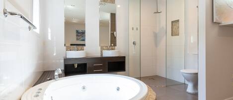 Een moderne badkamer met een vrijstaand bad, een douche met glazen wanden en een toilet.
