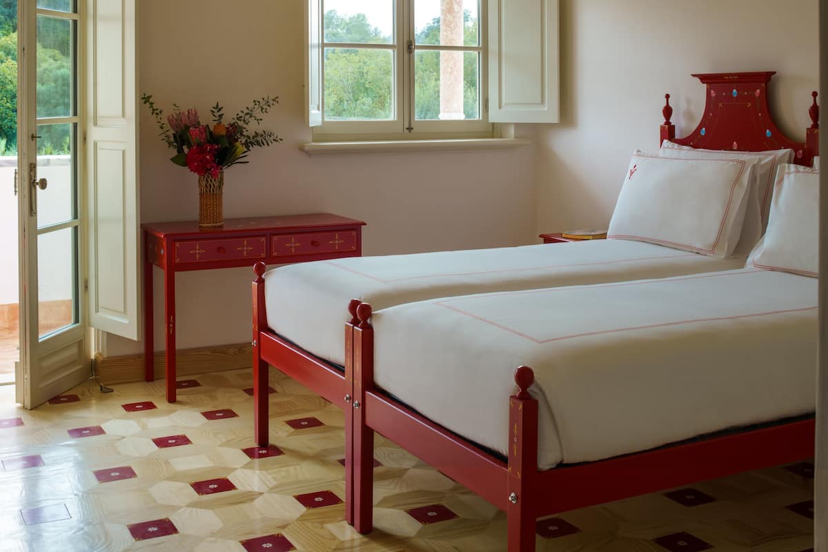 A bedroom with a bed, a window, a table, and a door.