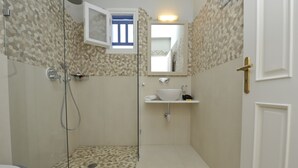 Ein Badezimmer mit Dusche, Toilette, Waschbecken und Spiegel.