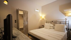 Ein Schlafzimmer mit Bett, Nachttischen, Fernseher und Lampe.