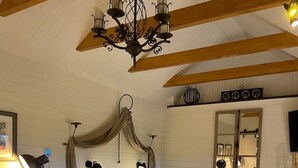 A bedroom with a large bed, a wooden headboard, a chandelier, a bedside table, a chair, and a mirror on the wall. - Charming stone Bothy at Loch Lomond (Muirlands, Arden, Alexandria, Luss,)
