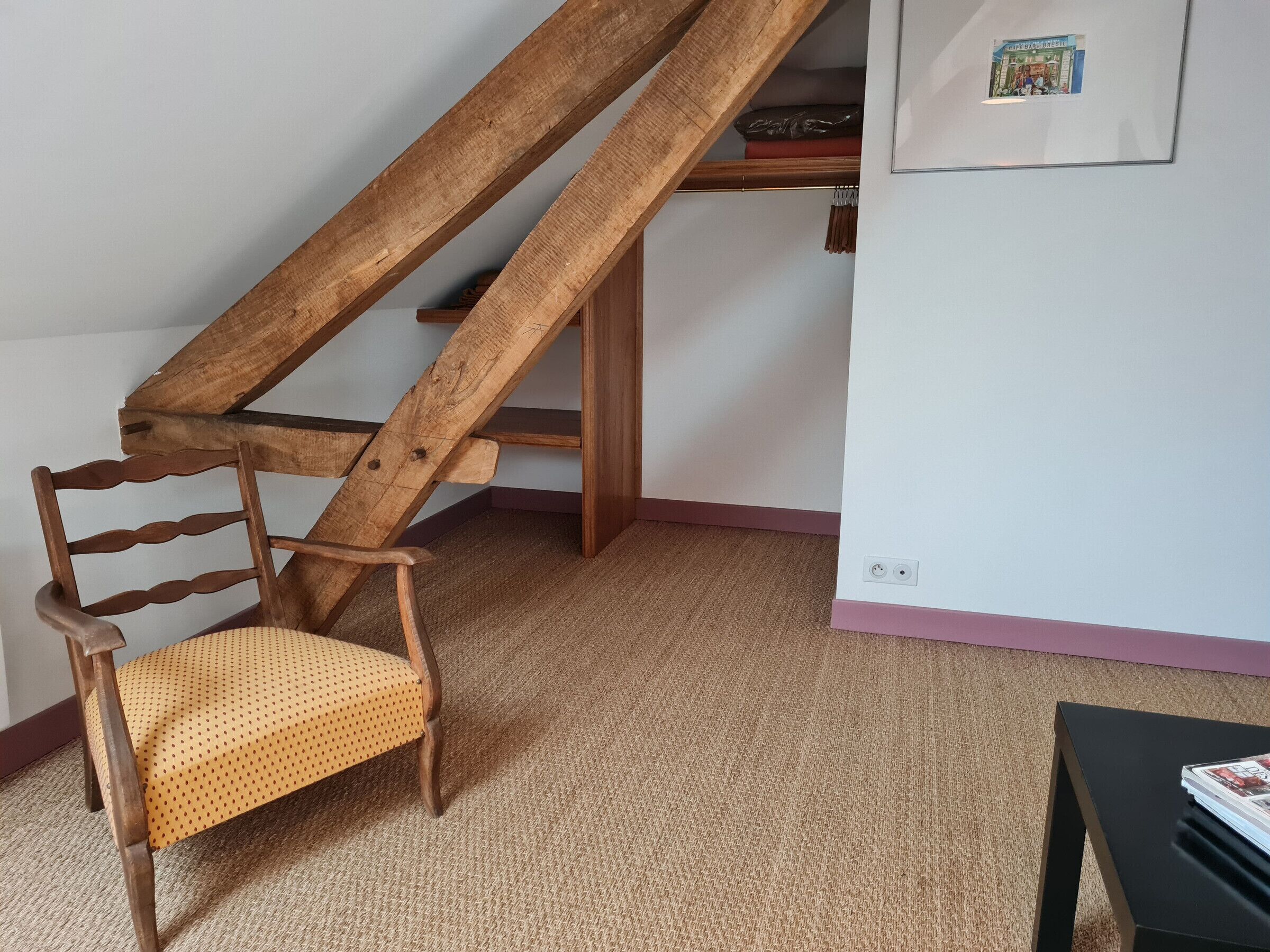 Ein Holzhocker mit gewebter Sitzfläche, eine Holztreppe und eine Wandsteckdose.