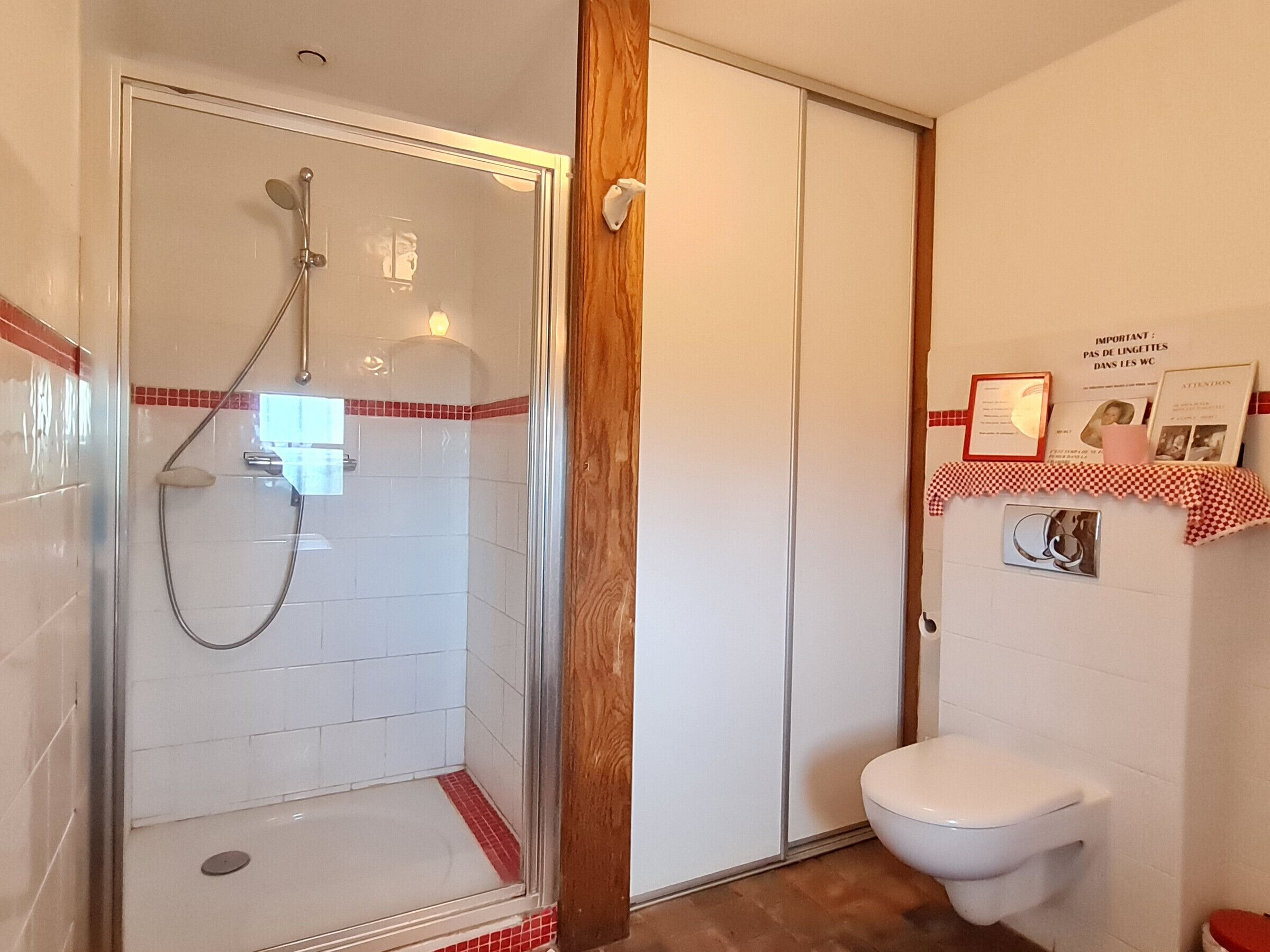 Un baño con cabina de ducha de vidrio, un inodoro y un estante con un cuadro enmarcado.