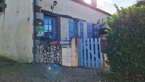 A building with a stone wall, a blue gate, and a sign indicating it is a Gîte. - Charming Cottage: Enclosed Garden, Close to Loire Valley, Sleeps 6 (Beaulieu-sur-Loire)