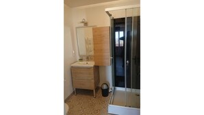 A bathroom with a sink, mirror, cabinet, and a glass shower enclosure.
