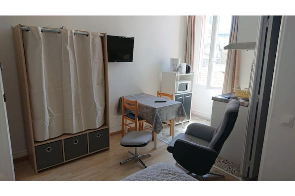 Una habitación pequeña con cama, escritorio, silla, televisor y ventana.