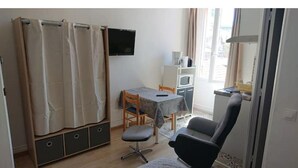 Una habitación pequeña con cama, escritorio, silla, televisor y ventana.