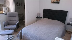 Un dormitorio con cama, una silla, una mesita de noche y un tocador.