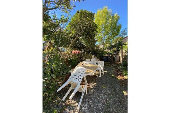 Zona de estar al aire libre con una mesa y sillas, rodeada de árboles y follaje.