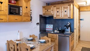 A compact kitchen with wooden cabinets, a microwave, a stove, and a refrigerator.