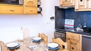 A compact kitchen with wooden cabinets, a microwave, a stove, and a dishwasher.