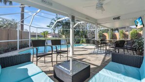 A covered outdoor area with a pool, seating, and a sign indicating 'Beach House'.