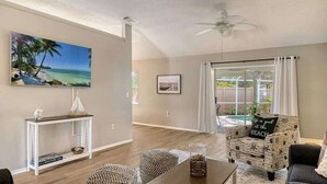 A living room with a beach-themed chair, a white console table, and a painting of a beach scene.