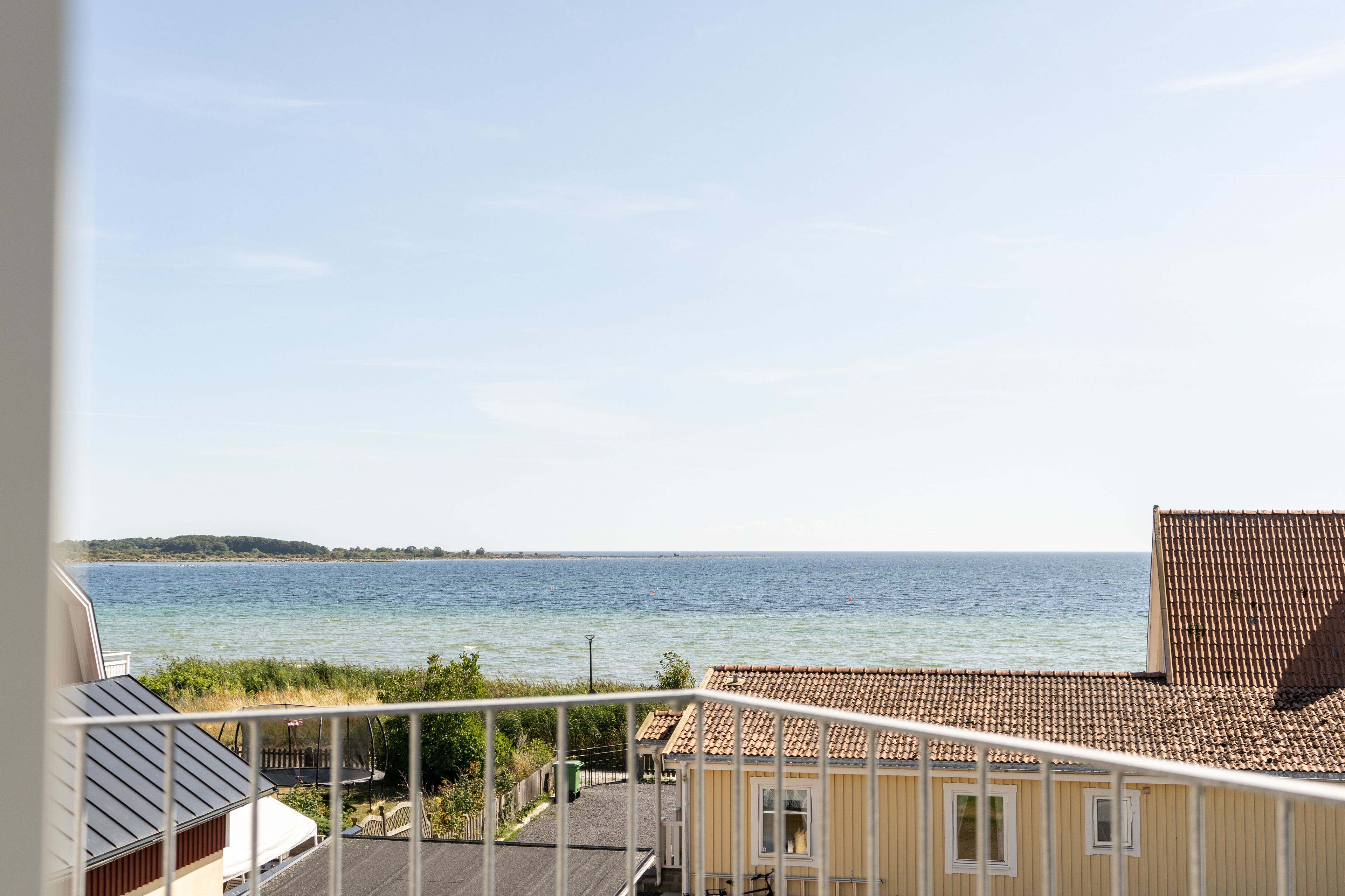 Un balcón con vista al mar y una costa distante.