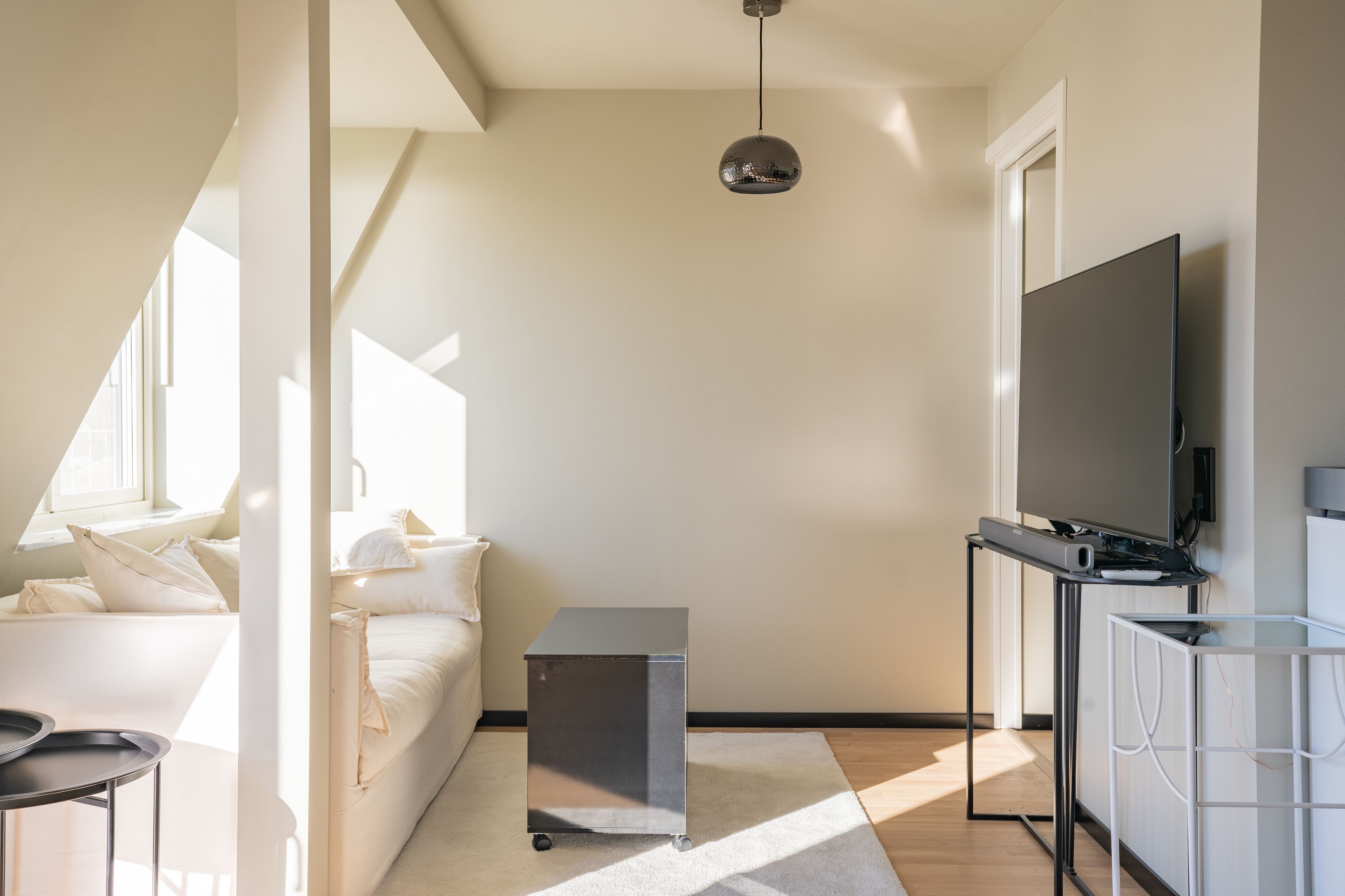 A modern living room with a sofa, a small table, a TV, and a cabinet.