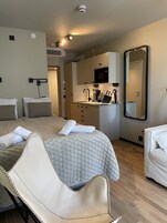 Una habitación de hotel con cama, zona de estar, kitchenette y baño.