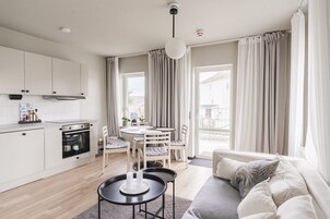 Una cocina moderna con armarios blancos, horno integrado y zona de comedor con mesa y sillas redondas.