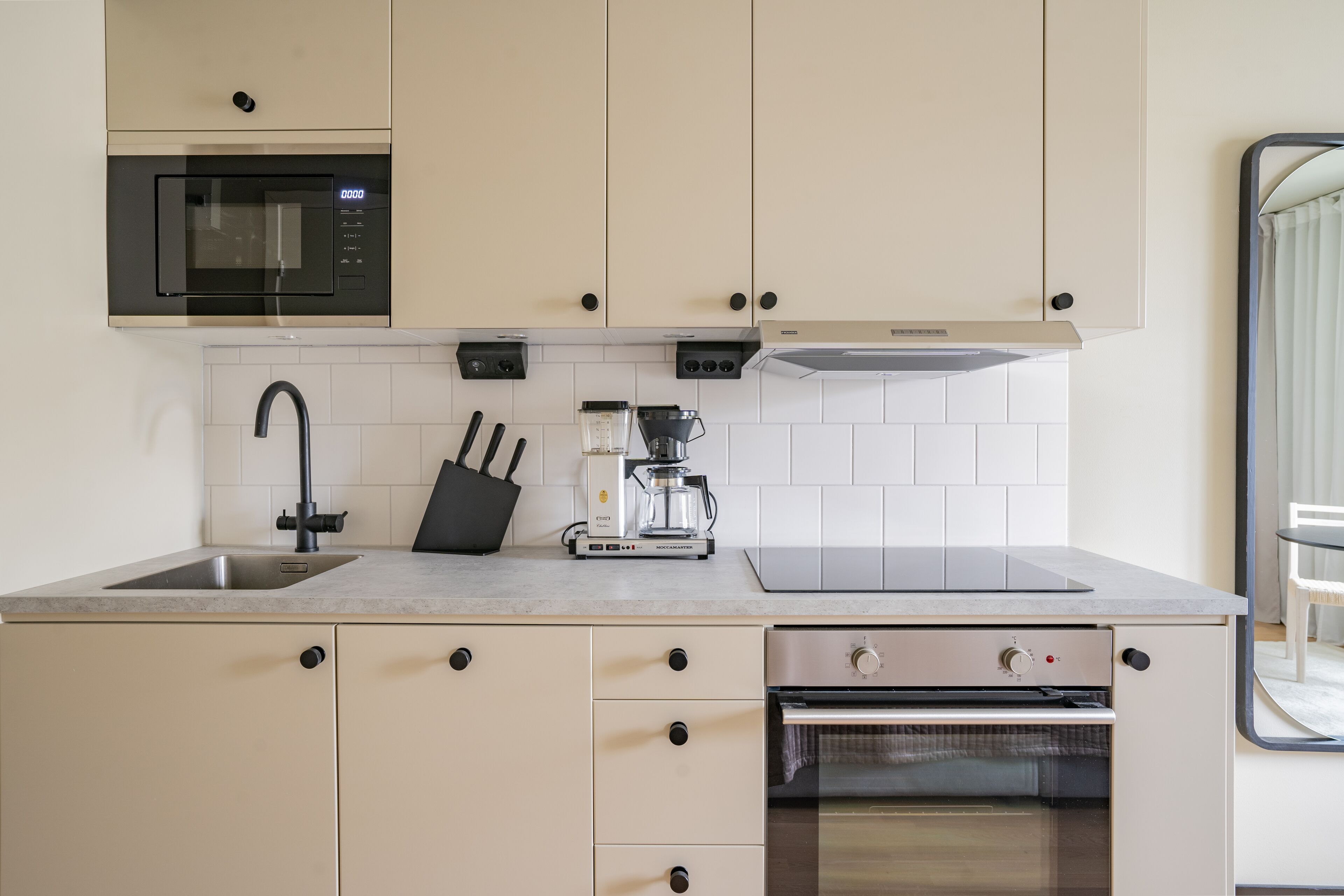 A modern kitchen with a built-in microwave, coffee maker, and oven.