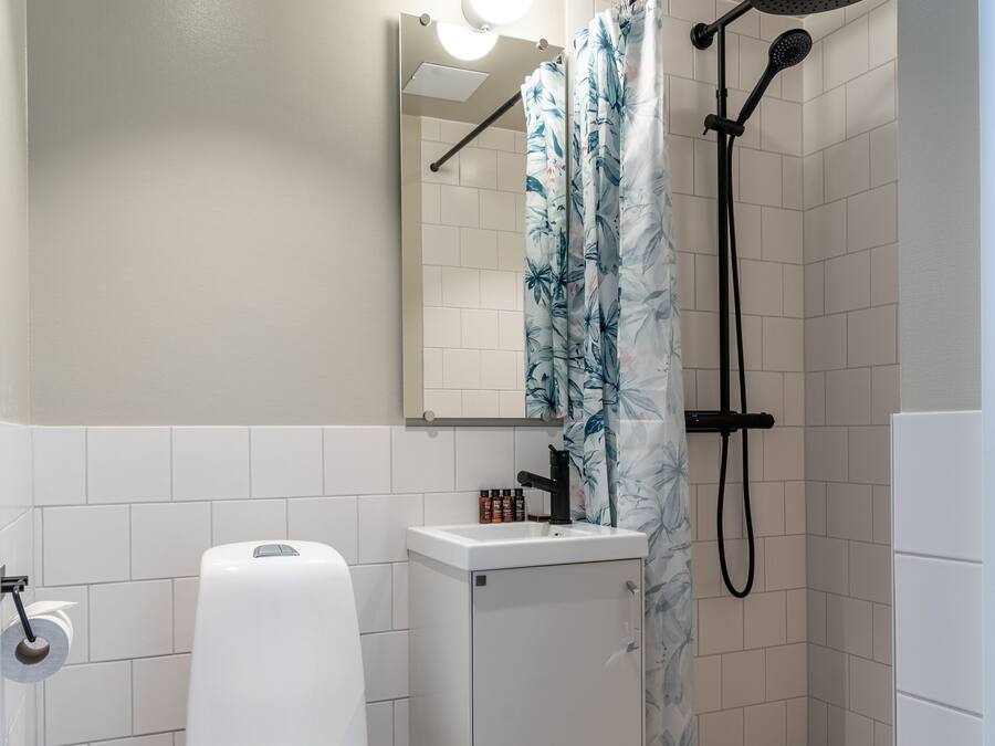 A bathroom with a toilet, sink, mirror, shower, and a towel rack.