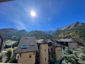 Un bâtiment doté de plusieurs toits, un ciel dégagé et des montagnes en arrière-plan.