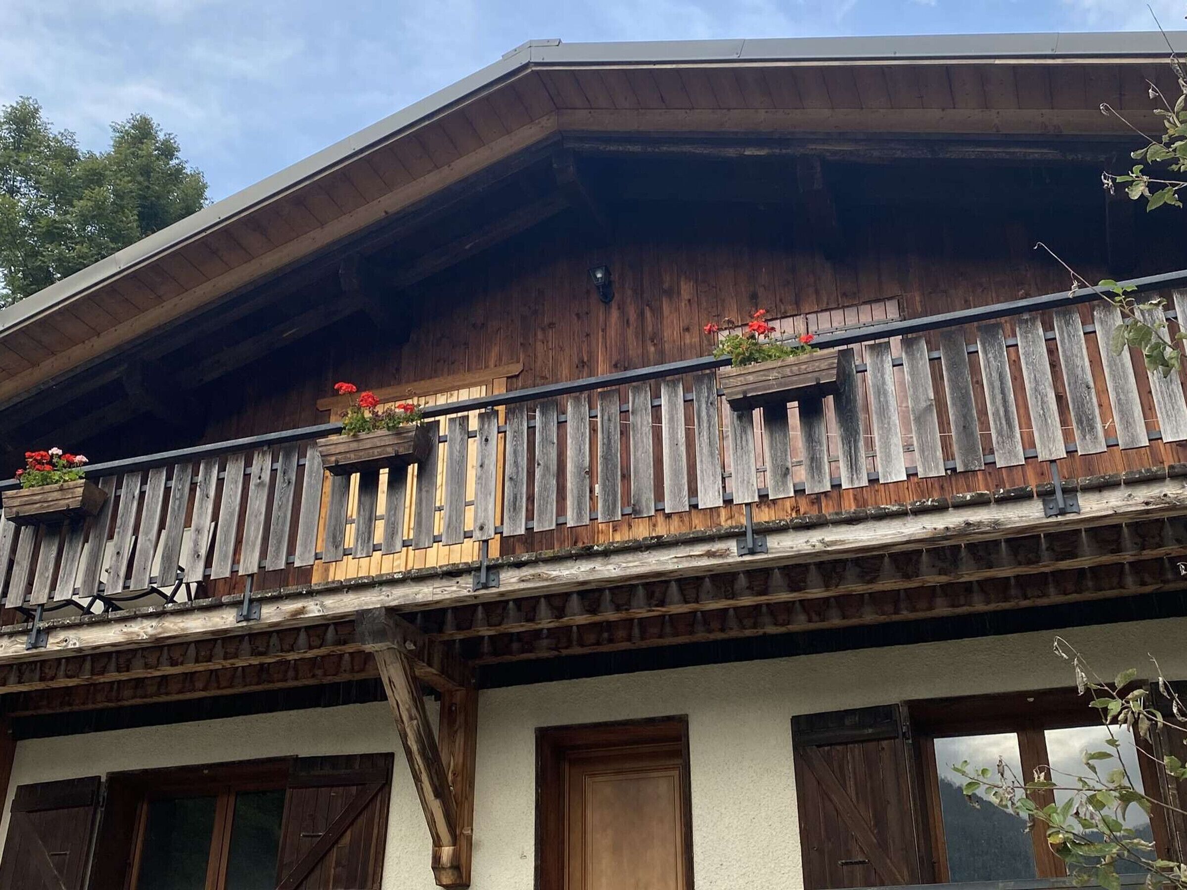 Un balcon en bois orné de jardinières et une façade de bâtiment au style rustique.