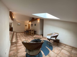 A spacious room with a dining area, a large window, and a ceiling skylight.