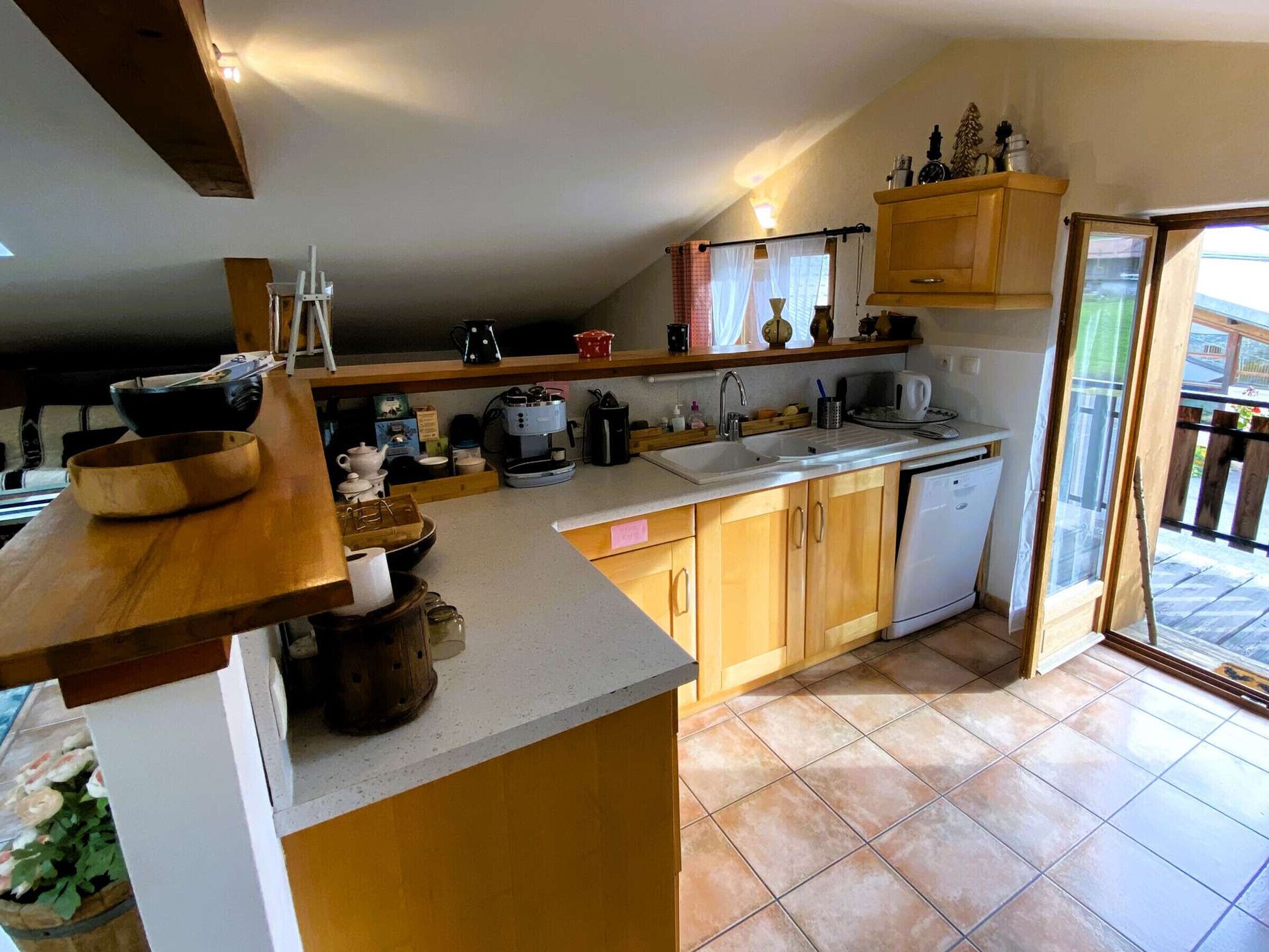 Une cuisine avec des meubles en bois, un évier, une machine à café et une fenêtre donnant sur un beau paysage.