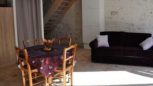 Ein Essbereich mit einem Tisch für vier Personen, einer dunkelgrauen Couch, einer Treppe und einem weißen Schrank.