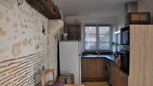Eine kleine Küche mit Holzschränken, einem weißen Kühlschrank und einem Fenster mit Jalousien.