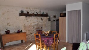 Ein gemütlicher Essbereich mit rustikaler Steinwand, Holzmöbeln und einem kleinen Tisch mit Stühlen.